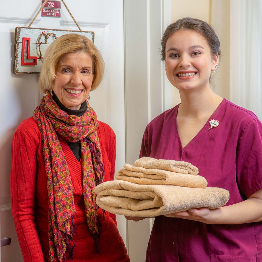 A team member delivering fresh linens to a resident at Heatherwood